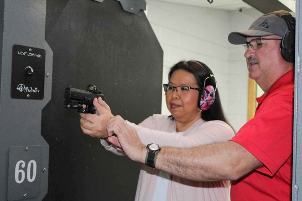 Instructor guiding shooter on handgun technique at indoor firing range